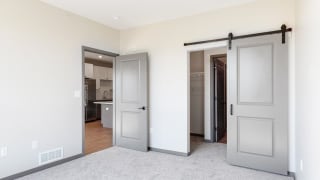 Sliding barn doors leading to closet space and the bathroom from the bedroom in the Bliss floor plan at Haven at Uptown in Lincoln, NE