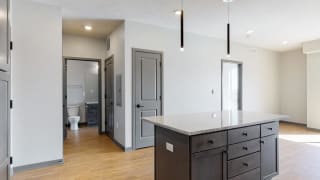 Bliss (1 bed, 1 bath) in Slate finish View of kitchen island and hallway leading to the bathroom in the Bliss floor plan at Haven at Uptown in Lincoln, NE