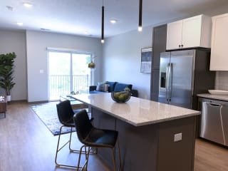 Furnished kitchen in the Slate finish with two tone cabinets, hard wood style flooring, and granite counter tops in the Bliss floor plan at Haven at Uptown