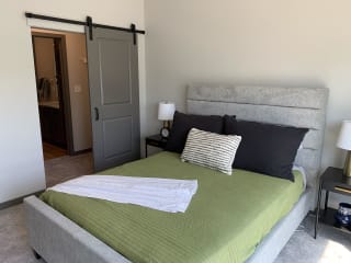 Furnished bedroom with sliding barn door leading to large walk in closet and bathroom at Haven at Uptown.