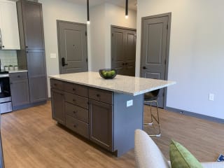 Large kitchen island with abundant storage and bar stools and pendant lights in the Bliss floor plan at Haven at Uptown in Lincoln.