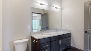 Dual sinks and light granite counter tops, as well is dark wood cabinetry for extra storage in the bathroom at Haven at Uptown in Linooln, NE