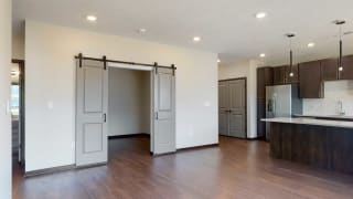 Melody (1 bed, 1 bath) in Mocha finish Living space with sliding barn doors leading to an office space in the Melody floor plan at Haven at Uptown in Lincoln, NE