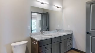 Dual sinks and light granite counter tops, as well is slate grey cabinetry for extra storage in the bathroom at Haven at Uptown in Linooln, NE