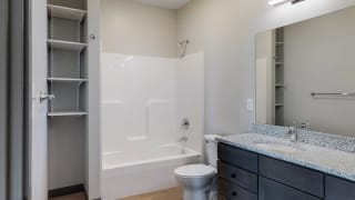 Bathroom with dual sink counter tops, a bathtub, and shelves for additional storage at Haven at Uptown in Lincoln, NE