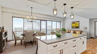 The fantastic chef&#x2019;s kitchen with seated island overlooks the spacious dining and living area 2 bedroom penthouse floor plan at Midtown Crossing Apartments Omaha.