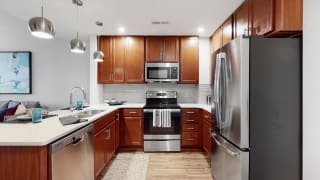 Spacious kitchen with peninsula and quartz or granite counter top and tile back splash in a 1 bedroom floor plan at Midtown Crossing Apartments Omaha