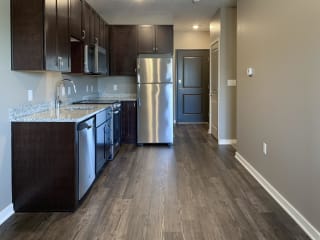 Kitchen with dark brown cabinets and matching stainless steel appliances in a studio apartment at the flats at shadow creek