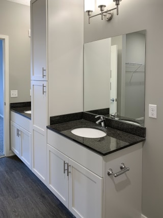 Bathroom with white vanity for storage and large mirror with great lighting at The Flats at Shadow Creek