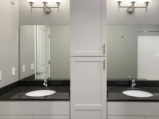 Bathroom with dual sinks and white cabinetry The Flats at Shadow Creek in Lincoln Nebraska