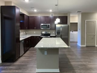 Kitchen with dark brown cabinets and large kitchen island and matching stainless steel appliances