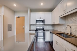 The Harriet features modern white cabinetry, stainless appliances,  quartz countertops,  a movable kitchen island