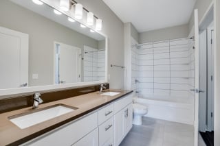 You&#x27;ll love the bathroom with dual vanities and custom-tiled tub and shower