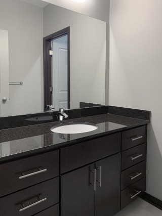 Bathroom with dark brown vanity and linen cabinet for storage and large mirror