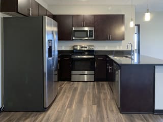 Kitchen with dark brown cabinets and matching stainless steel appliances at the villas at mahoney park