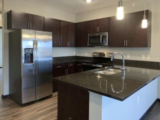 Kitchen with dark brown cabinets and matching stainless steel appliances in a the grand canyon floorplan at the villas at mahoney park