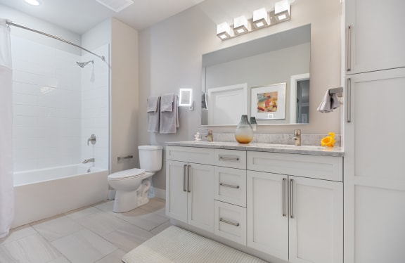 a bathroom with white cabinets and a white bathtub