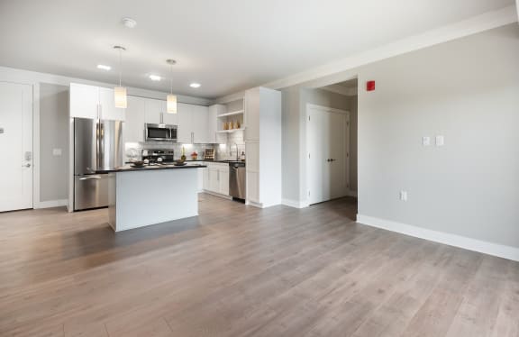 a spacious living room with a kitchen in the background