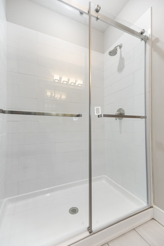 a white tiled shower with a glass door