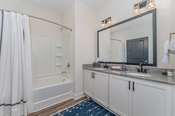 a bathroom with white cabinets and a blue rug