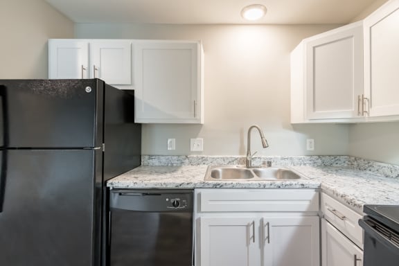 a kitchen with white cabinets and black appliances
