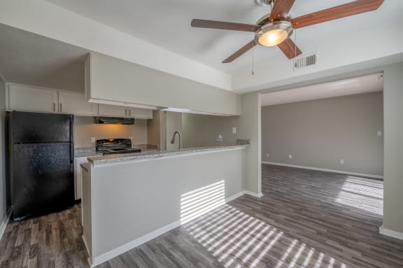 a kitchen and living room with a ceiling fan