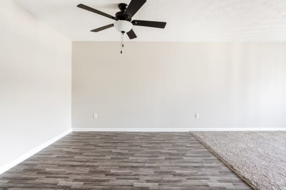 an empty room with a ceiling fan and a rug
