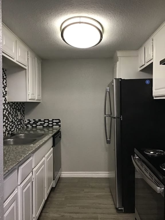 a kitchen with white cabinets and a black refrigerator