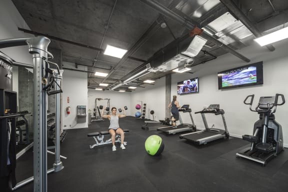 Gym with treadmills, an elliptical, weight machines, free weights, benches, an exercise ball and tvs