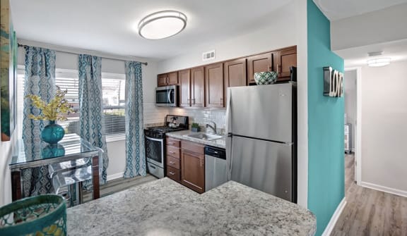 Luxury 2 bedroom apartment kitchen with dark wood cabinets and stainless steal appliances. Wood like flooring is throughout.