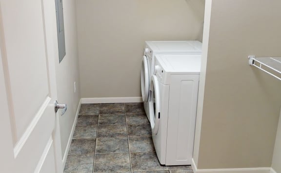 In-unit washer/dryer with a storage shelf next to it.