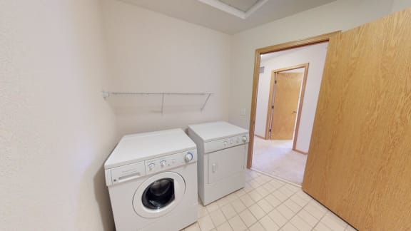 Washer and dryer in small tiled room with shelf above