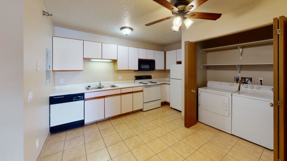 Kitchen with white cabinets and adjacent closet which contains side by side washer and dryer