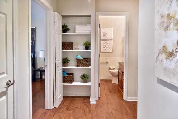 Hallway Closet next to Bathroom with Multiple Shelves of Plants and Laundry Baskets