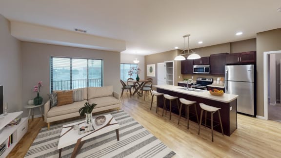 Spacious living area that leads into the open kitchen with an island, stainless steel appliances, and a separate dining area.