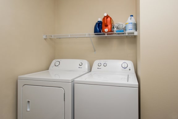 In-unit washer and dryer combo underneath shelf with laundry supplies