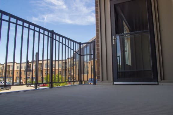 Low angle shot of a private balcony with metal railing and glass door leading inside