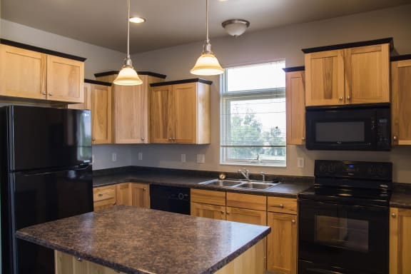 Full kitchen with light wood cabinets, black appliances and central island