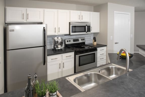 Kitchen with stainless steel appliances, white cabinetry and breakfast bar with sink