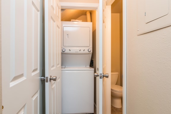 In unit washer and dryer stacked on top of each other inside closet next to bathroom