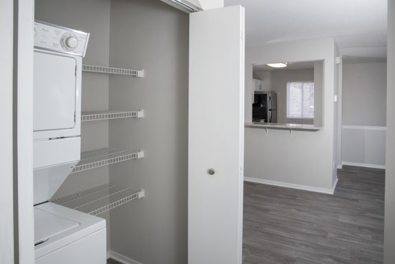 Closet in hallway open with stacked washer and dryer combo and additional shelving