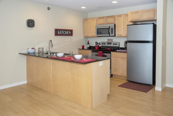 Kitchen with island, light wood cabinetry and stainless steel appliances