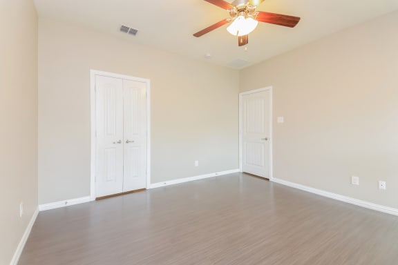 Bedroom with ceiling fan and light through windows at Brooklyn Village Forney, Forney, TX, 75126