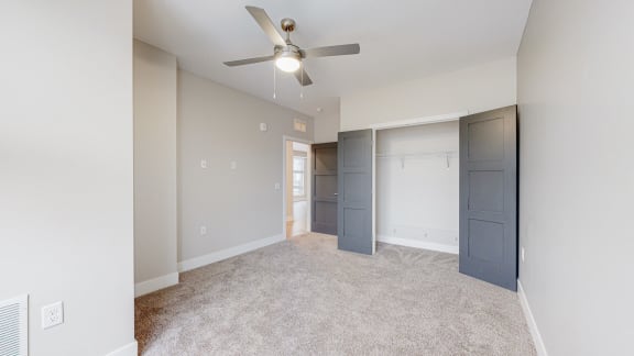 a bedroom with a ceiling fan and two closets