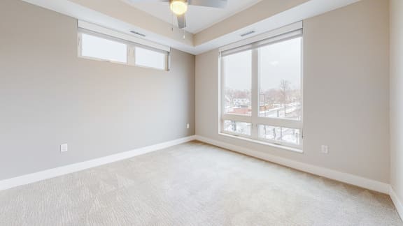 a master bedroom with two windows and a carpeted floor