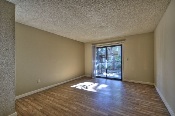 Vacant apartment home with hardwood inspired flooring through out.  Views of the sliding glass patio door.