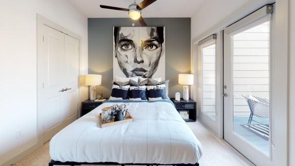 Bed with two nightstands facing a large portrait next to exterior patio