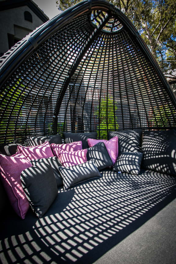 Egg shaped lounge chair with multicolor throw pillows.