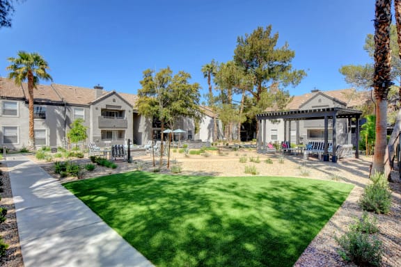 Multiple outdoor seating areas with lush landscaping and apartments surrouding.