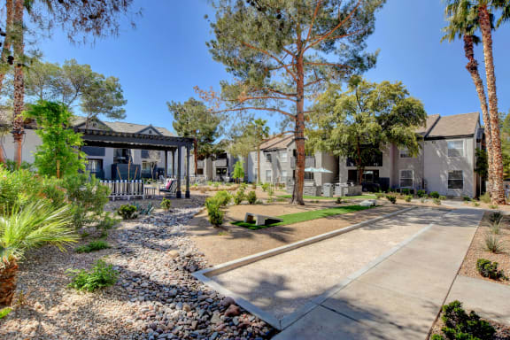 Outdoor area with corn hole and a covered seating area with apartments surrounding.